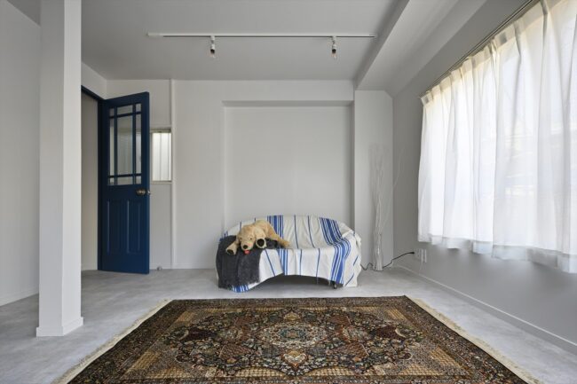 重厚な絨毯が敷かれているこのスペースも壁は全面白であり、犬のぬいぐるみとソファが設置されております。