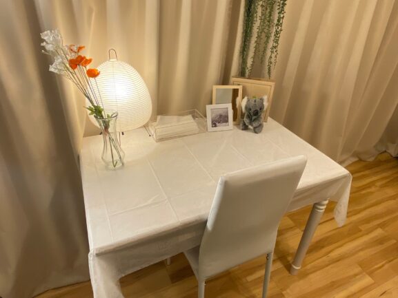 白いテーブルの上にはカワイイお花と照明や写真が置かれております。