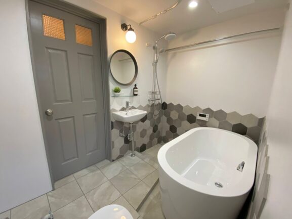タイル状のデザインを施したバスルーム。楕円形の浴槽がオシャレです。